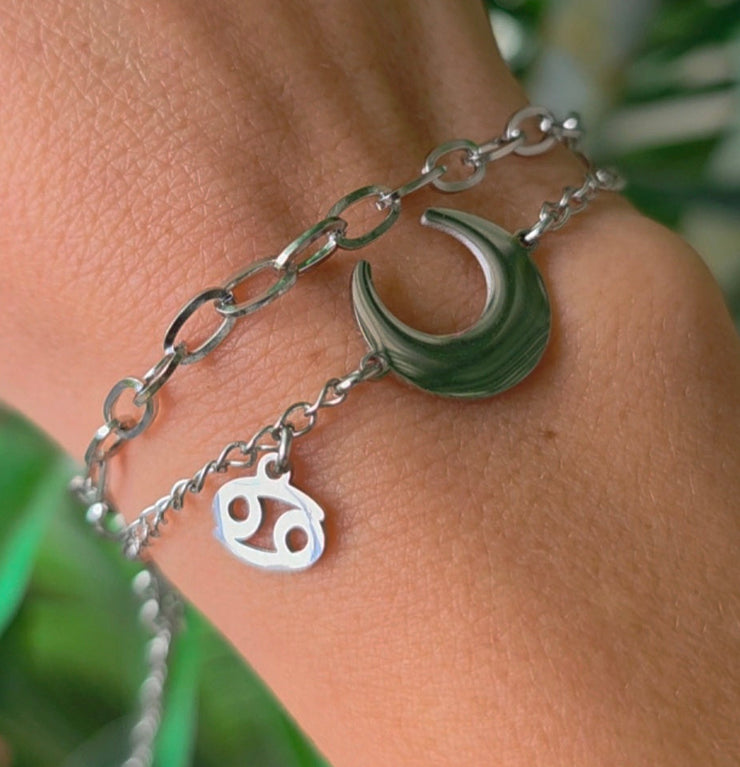 Bracelet argenté en acier inoxydable avec pendentif Lune et symbole astrologique du Cancer, création Therapietra, porté au poignet.