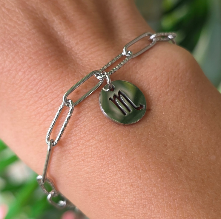 Bracelet argenté en acier inoxydable avec pendentif astrologique du Scorpion, création Therapietra, porté au poignet.
