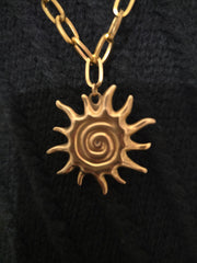 Détail du pendentif Soleil du Collier Sautoir Divina, bijou doré lumineux en acier inoxydable, symbole de puissance et de lumière intérieure.